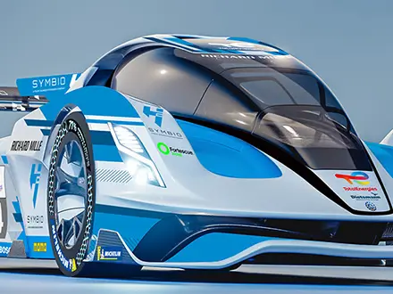 Side view of a futuristic endurance race car with blue and white livery and number 24, displayed indoors under a geodesic exhibition structure with sponsor logos visible.